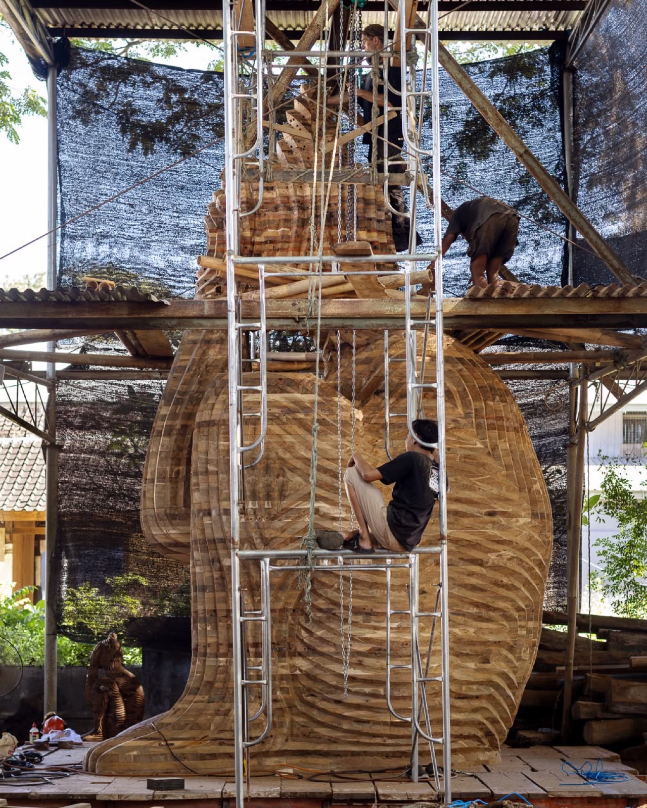 Side view of the in-progress sculpture with workers on the scaffold
