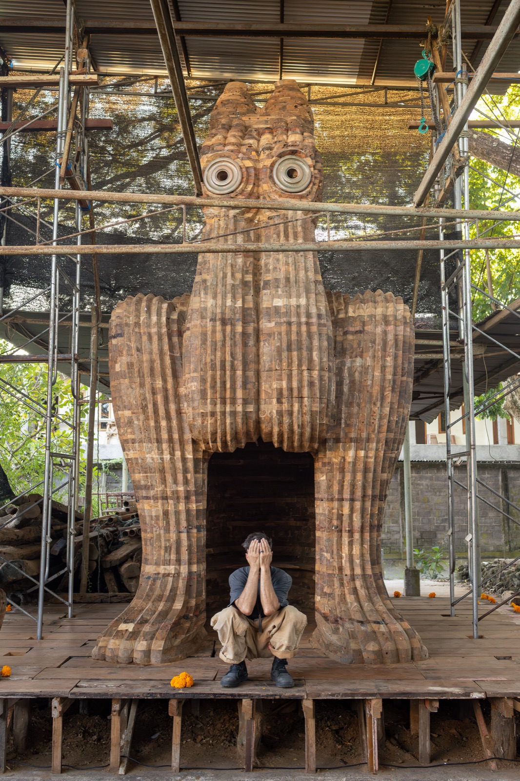 Spencer Hansen crouched with hands over his eyes beneath the finished Behind Closed Eyes sculpture