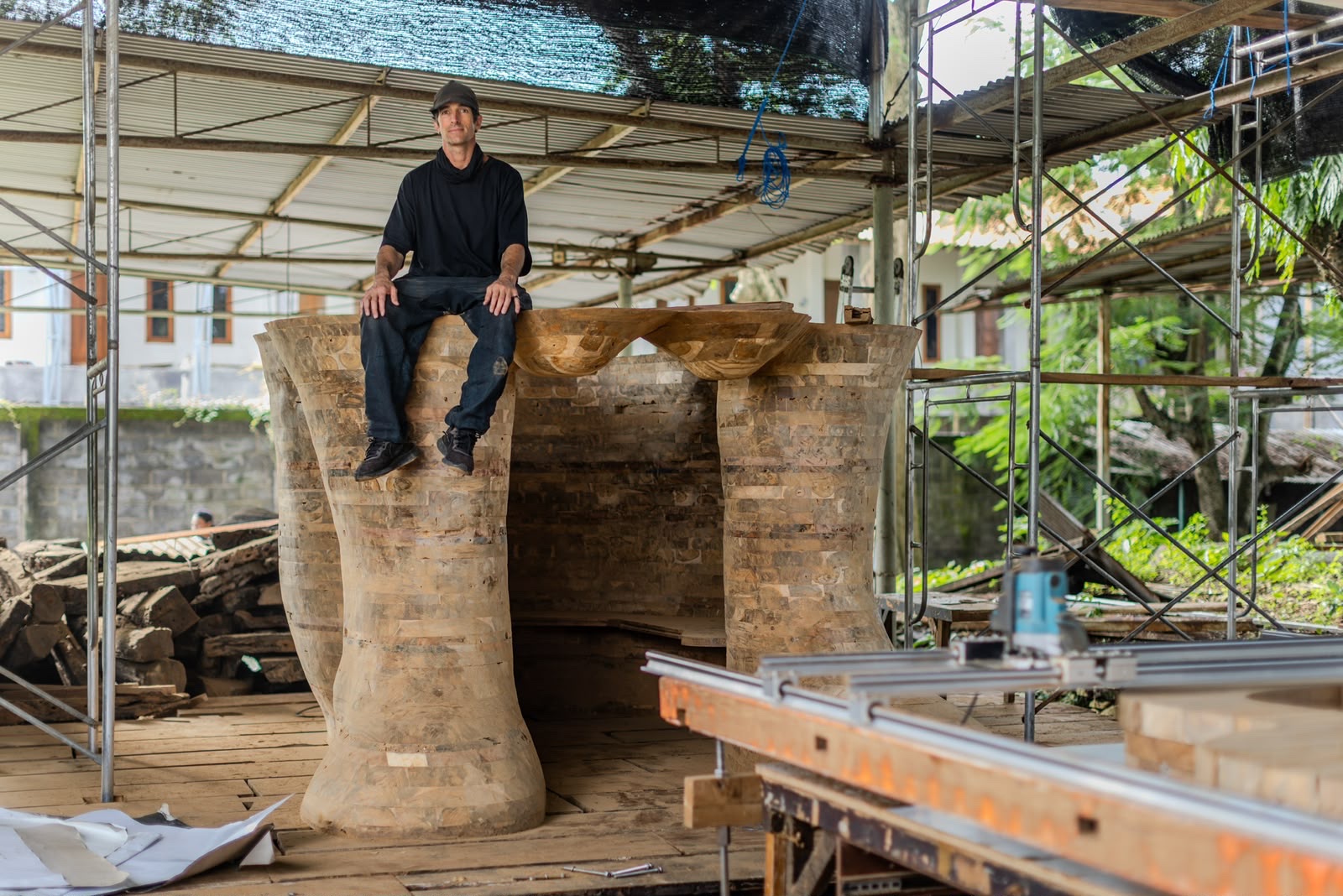 Spencer Hansen sitting on top of the Behind Closed Eyes sculpture in the Bali workshop